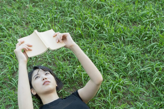 Joven asiática leyendo un libro en el parque