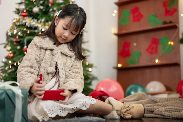 Una joven asiática linda y feliz está abriendo un regalo de Navidad en la sala de estar