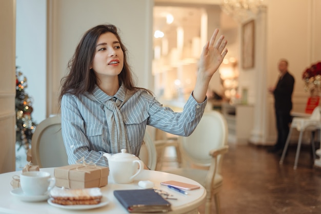 Foto joven asiática llamando a la camarera en café