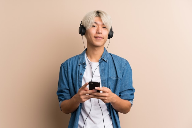 Joven asiática manusing el móvil con auriculares