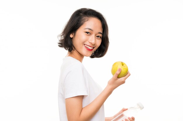 Joven asiática con una manzana y una botella de agua