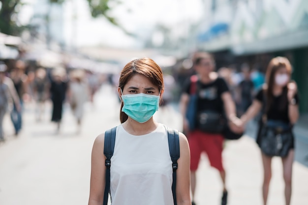 Joven asiática con máscara de protección contra el nuevo coronavirus (2019-nCoV) o el coronavirus Wuhan en el mercado de fin de semana de Chatuchak, punto de referencia y popular para las atracciones turísticas