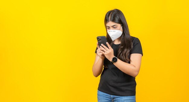 Joven asiática con una mascarilla médica en ropa informal aislada de fondo amarillo