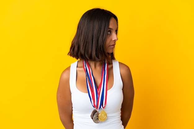 Joven asiática con medallas aislado en blanco mirando hacia el lado