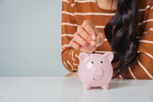 Foto joven asiática con moneda de dinero y hucha