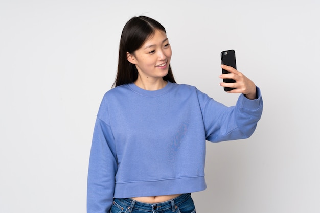 Joven asiática en la pared haciendo un selfie