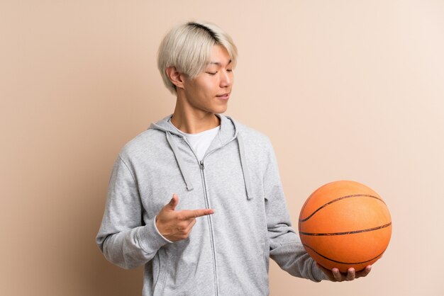 Joven asiática con pelota de baloncesto y apuntando