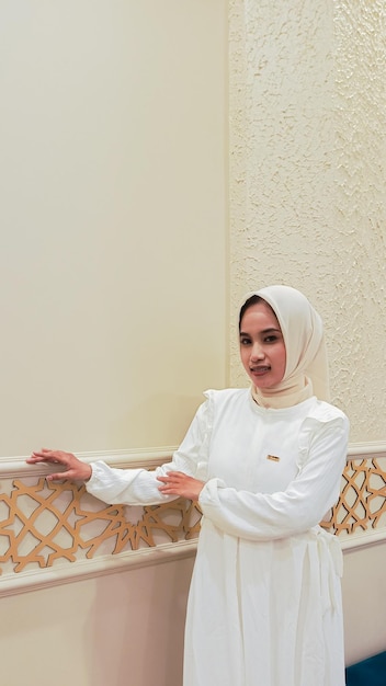 joven asiática de pie expresión de sonrisa mano apoyada contra la pared con atmósfera árabe islámico