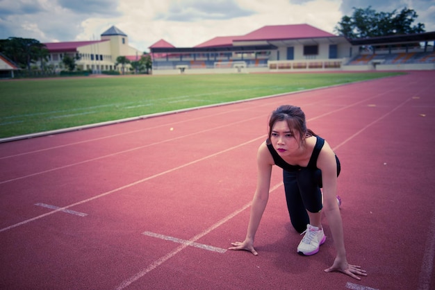 Joven asiática en una posición de inicio en una pista de atletismo