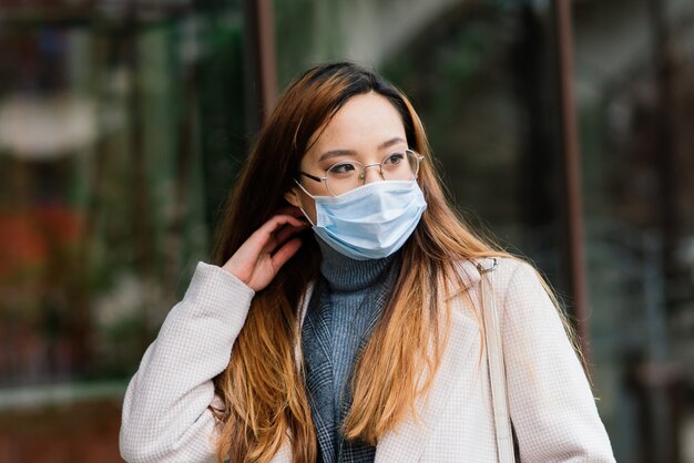 Joven asiática con protección facial mascarilla quirúrgica