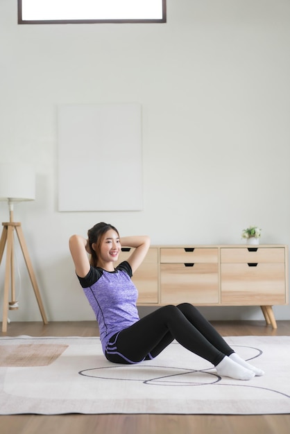 Joven asiática puso las manos detrás de la cabeza para hacer ejercicio y hacer ejercicio para un estilo de vida saludable en casa