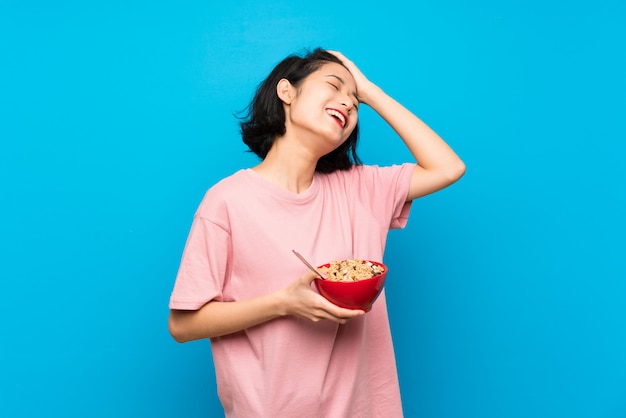 Una joven asiática que sostiene un tazón de cereales se ha dado cuenta de algo y pretende la solución.