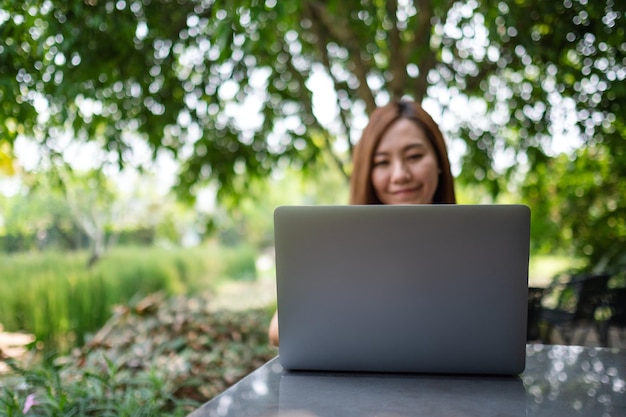 Una joven asiática que usa y trabaja en una computadora portátil en el parque