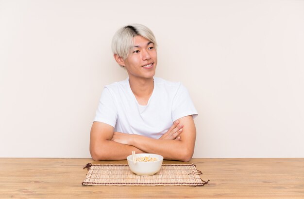 Joven asiática con ramen en una mesa mirando hacia el lado