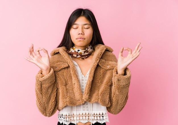 Joven asiática se relaja después de un duro día de trabajo, ella está realizando yoga.