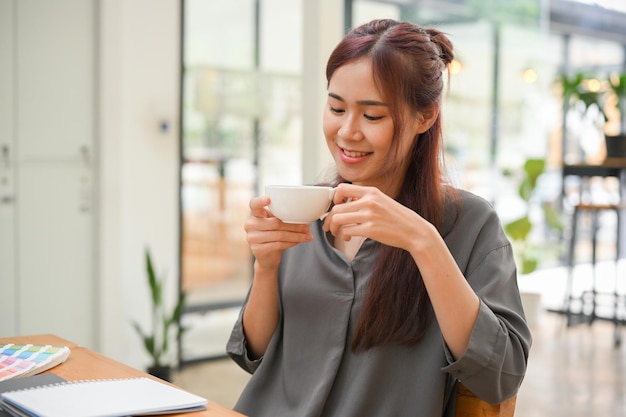 Una joven asiática relajada disfruta tomando café por la mañana en la cómoda cafetería