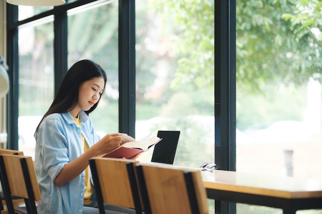 Joven asiática sentada y leyendo un libro