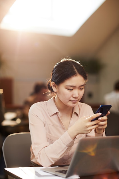 Joven asiática con smartphone en café