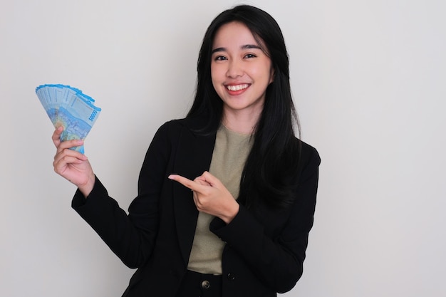 Joven asiática sonriendo y señalando el dinero que tiene