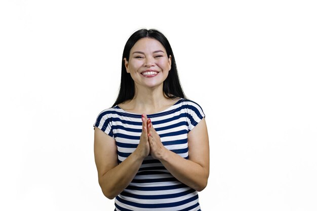 Una joven asiática sonriente gestando un saludo o un gesto de oración aislado en blanco