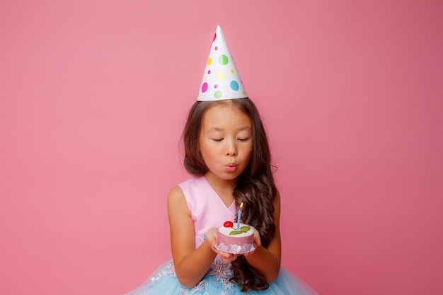 Una joven asiática sopla una vela en una rosa en una fiesta de cumpleaños