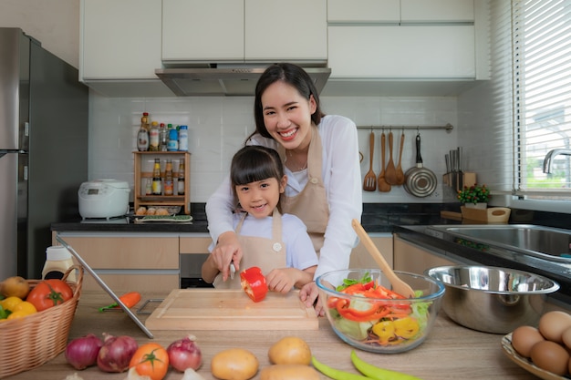 Joven asiática y su hija cocinar ensalada para el almuerzo.