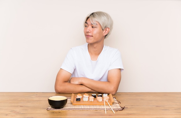 Joven asiática con sushi en una mesa de pie y mirando hacia un lado