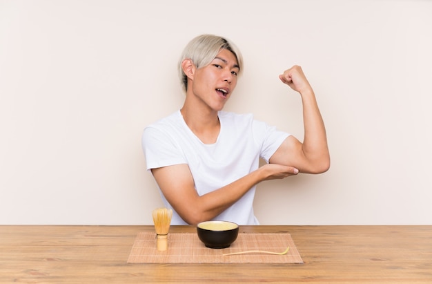 Joven asiática con té matcha en una mesa haciendo un gesto fuerte