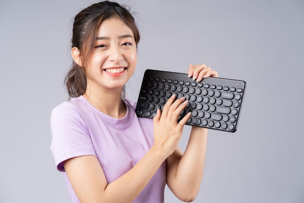 Joven asiática con teclado en gris