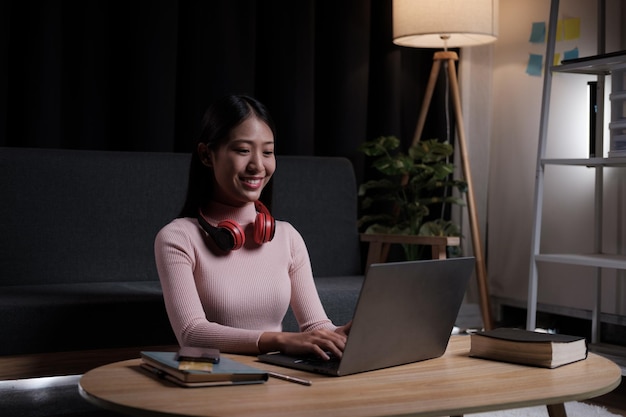 Una joven asiática tiene una videoconferencia en línea mientras está sentada dentro de su casa por la noche
