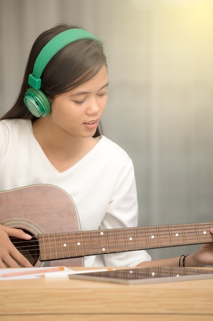 Foto joven asiática tocando la guitarra y tratando de ser compositor de música, compositor de canciones