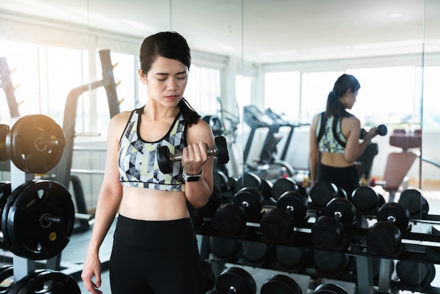 Foto joven asiática trabajando con pesas en el gimnasio