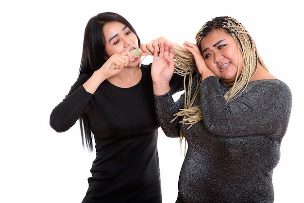 Joven asiática transgénero comiendo y tirando del cabello de su amiga