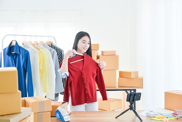 Joven asiática vendiendo ropa en línea por transmisión en vivo