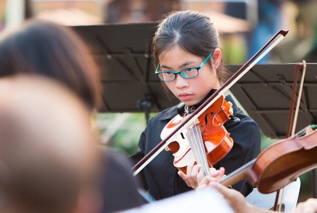 Joven asiática violinista actuando en un concierto al aire libre