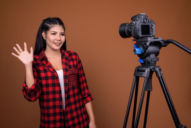 Joven asiática vlogging en estudio con cámara en trípode