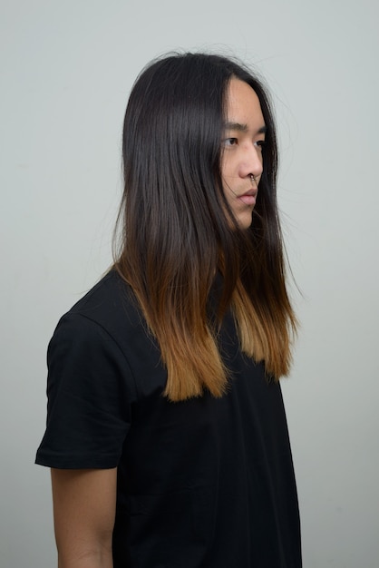 Joven asiático con cabello largo pensando