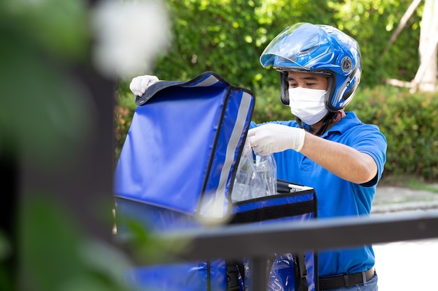 Joven asiático con caja de entrega Motocicleta que entrega el concepto de servicio express de comida