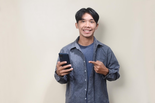 Joven asiático con camisa gris usando el teléfono en un fondo aislado