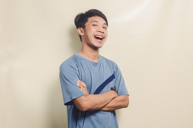 Joven asiático en camiseta deportiva que parece feliz aislado en el fondo