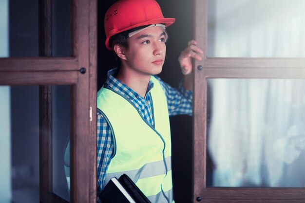 Joven asiático con casco protector y chaleco de construcción