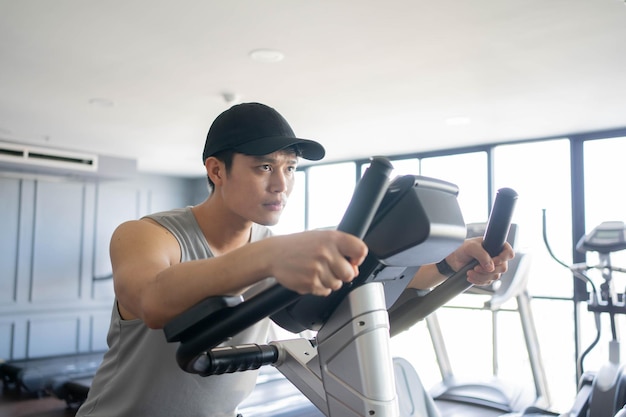 Foto un joven asiático corre en una máquina de bicicletas estáticas para practicar y hacer ejercicio