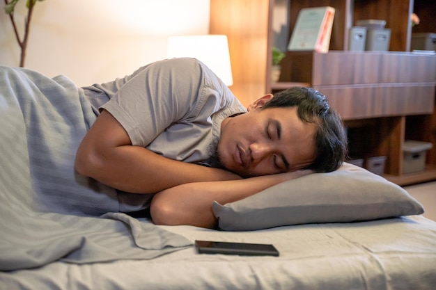 Joven asiático durmiendo en la cama