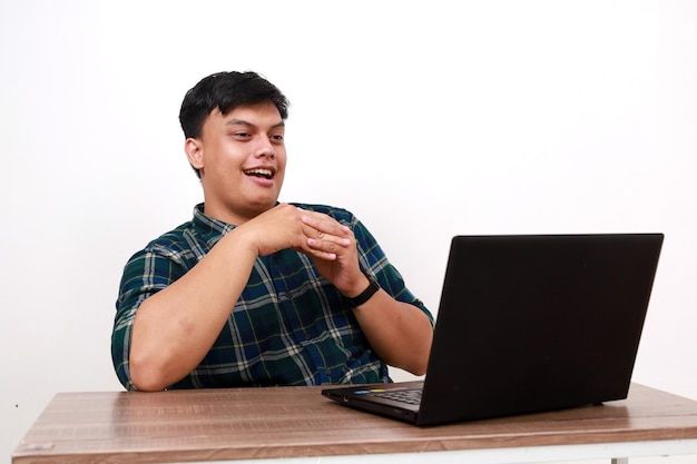 Joven asiático emocionado con algo en su portátil con expresión facial sonriente