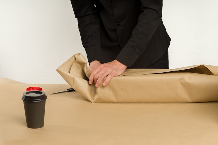 Foto joven asiático empaqueta un paquete de regalo sobre la mesa - imagen