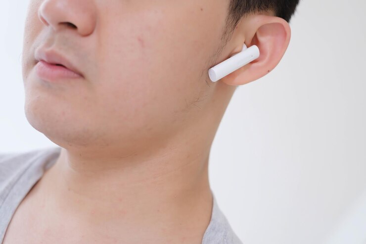 Un joven asiático escuchando auriculares estéreo inalámbricos verdaderos blancos