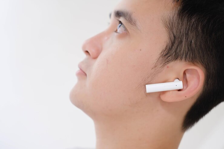 Un joven asiático escuchando auriculares estéreo inalámbricos verdaderos blancos