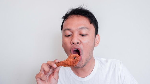 Joven asiático está comiendo pollo frito con camisa blanca