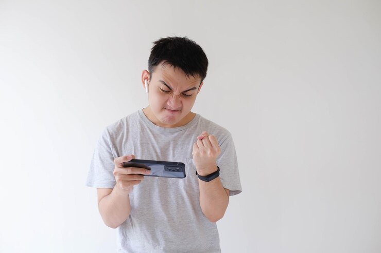Un joven asiático está enojado mientras juega en su teléfono inteligente