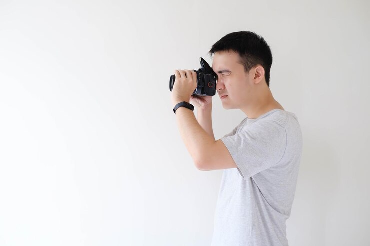 Un joven asiático está fotografiando y dirigiendo una cámara DSLR con el flash abierto